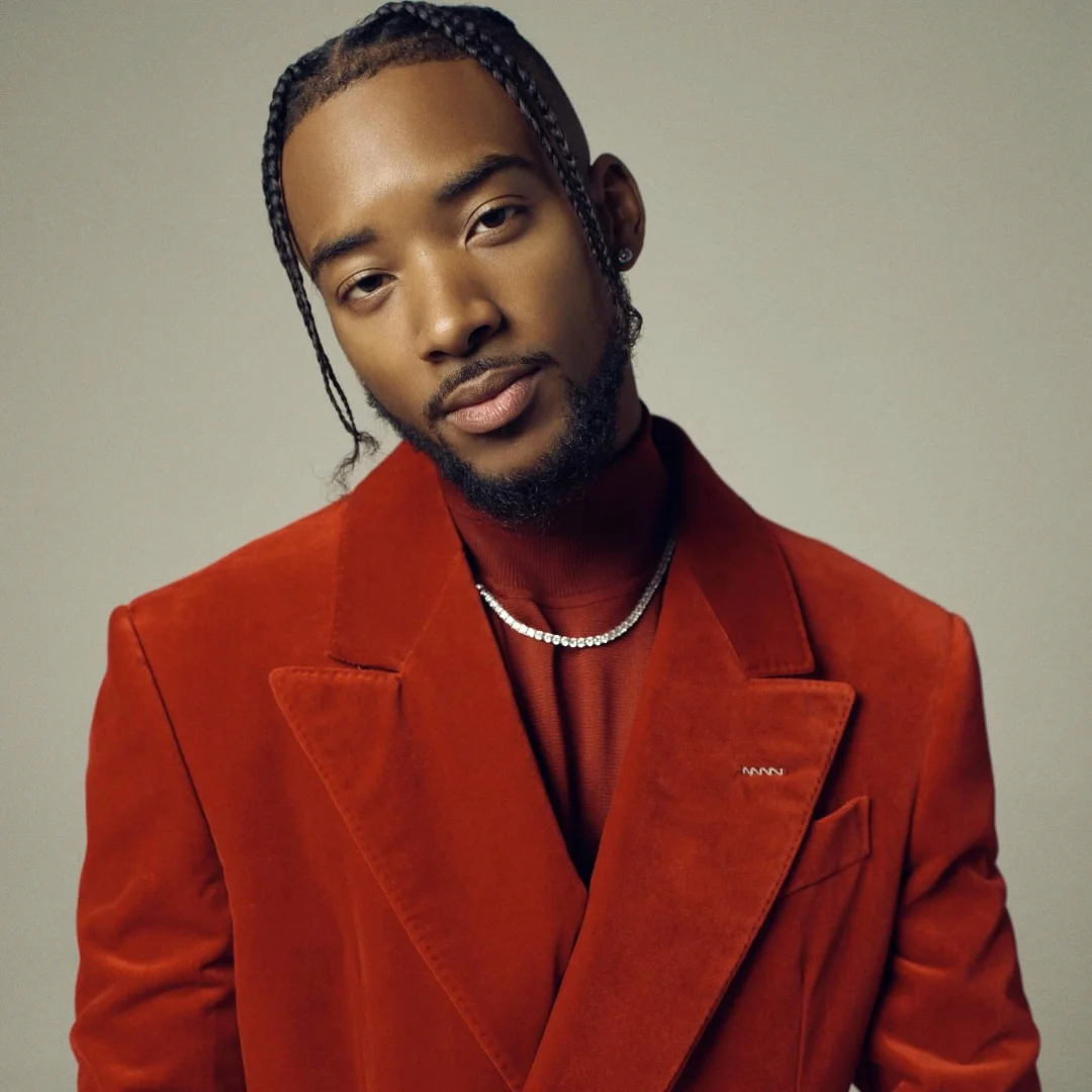 Algee Smith in a stylish red velvet blazer, posing confidently.