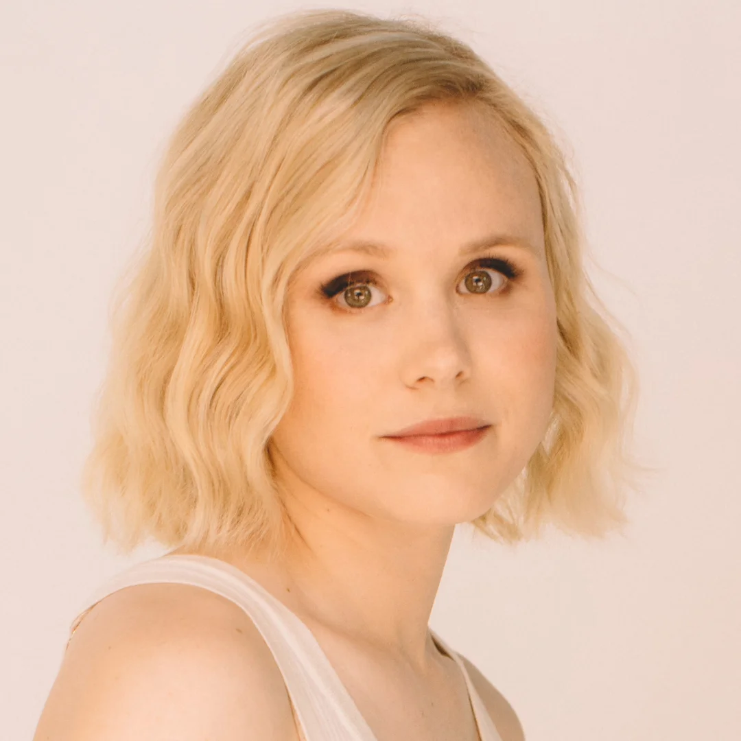 Alison Pill with blonde hair, looks at the camera.