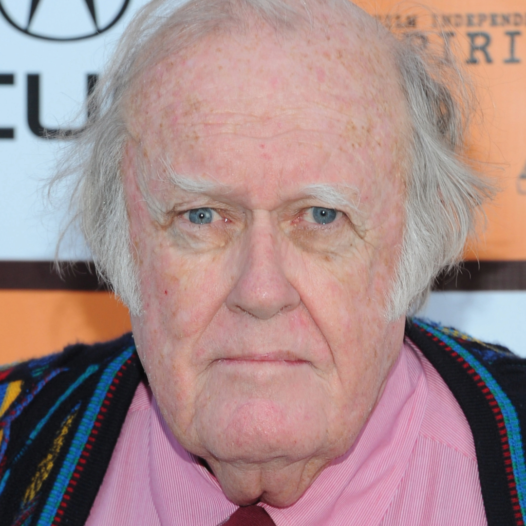 M. Emmet Walsh at an event, wearing a pink shirt and a colorful sweater.