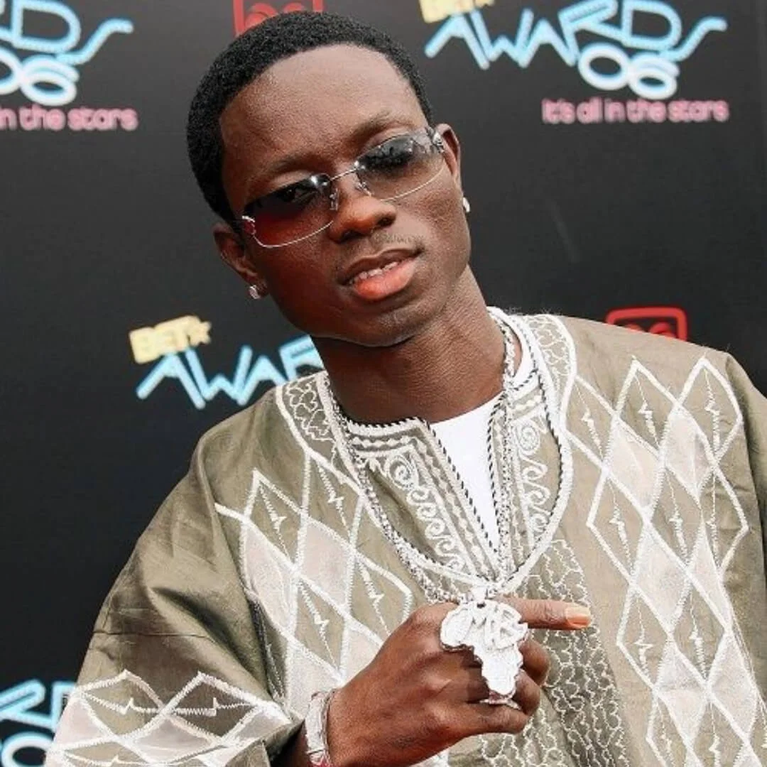 Man wearing sunglasses and a patterned outfit with necklaces at the BET Awards.