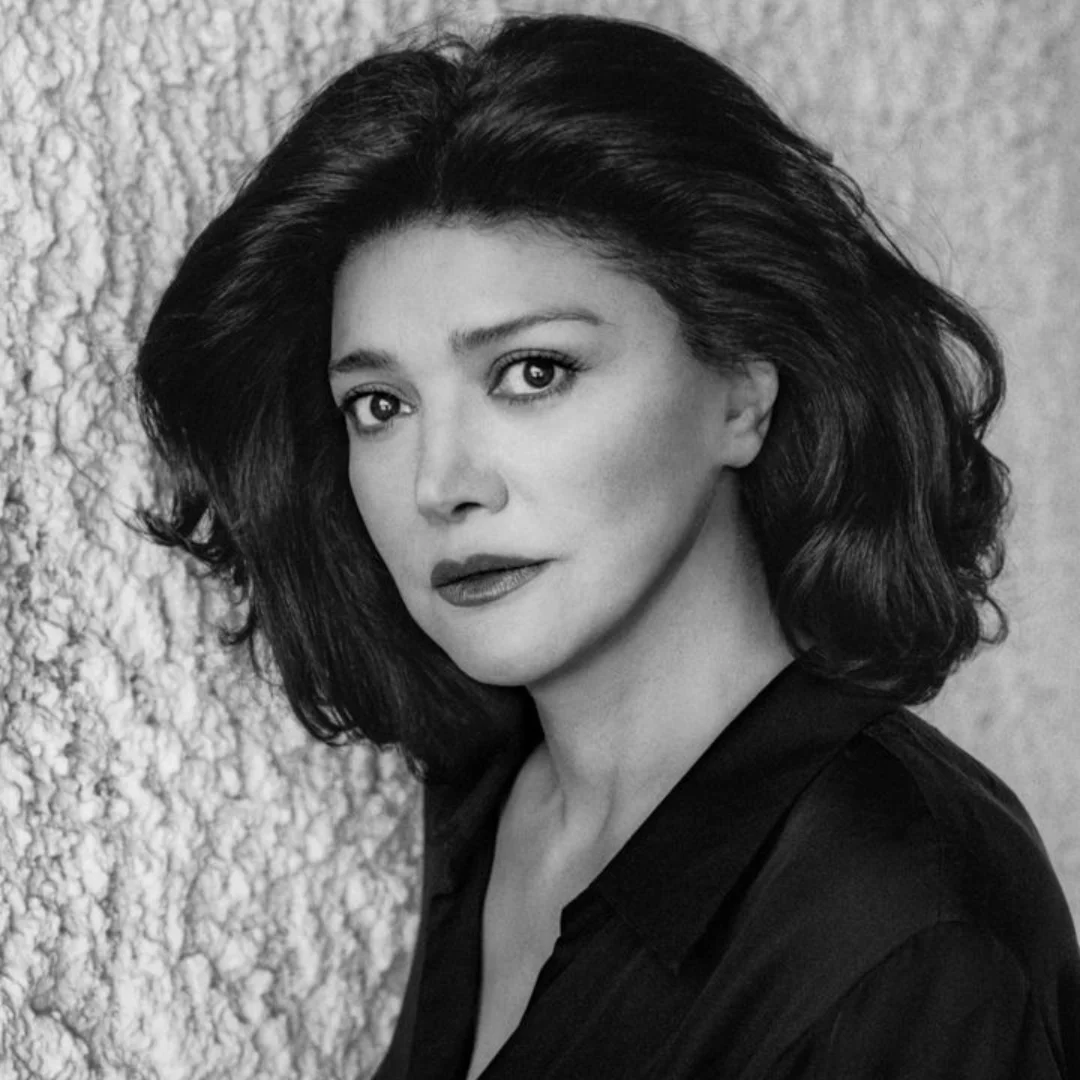 Black and white portrait of a woman with dark hair against a textured wall.