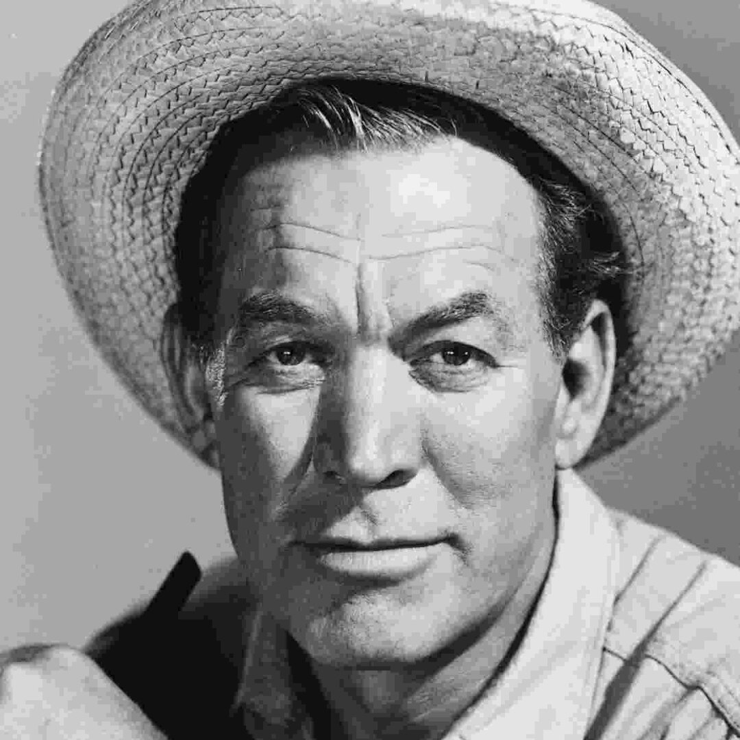 Black and white portrait of a man wearing a straw hat, with a serious expression and a plain background.