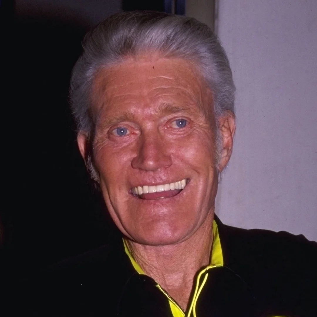 Chuck Connors, American actor and athlete, smiling at an event.