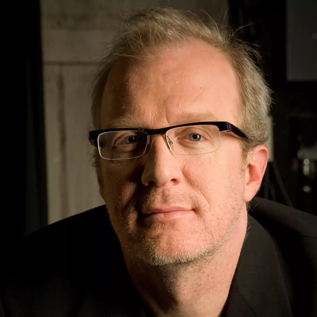 Tracy Letts wearing glasses, looking at the camera with a serious expression.