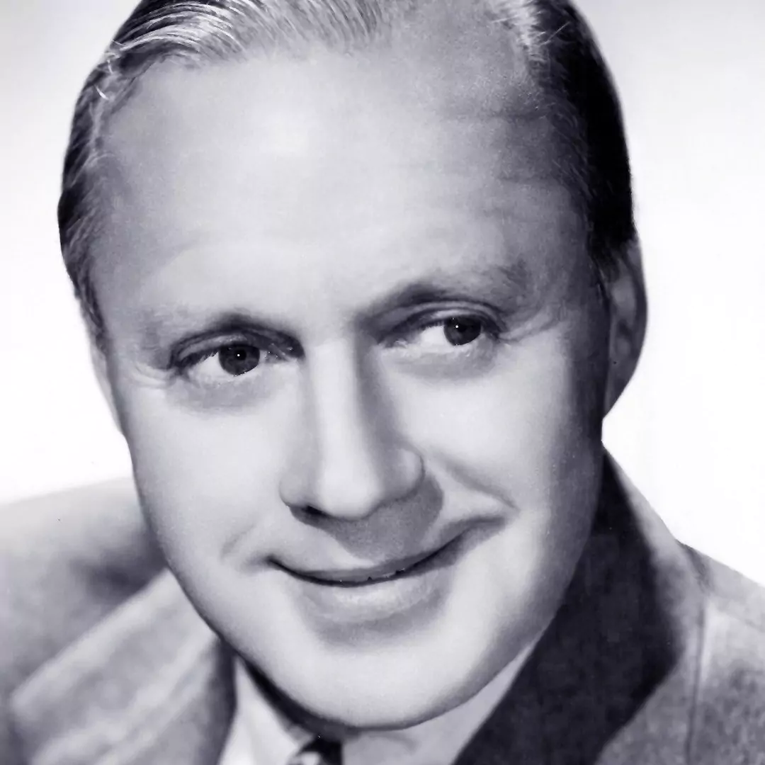 Black and white portrait of a smiling man with neatly combed hair, wearing a suit